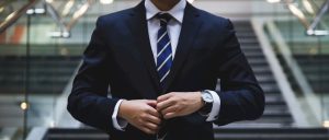 Man straightens suit jacket in outdoor setting