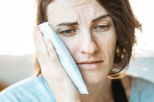 Person holding ice pack against their jaw